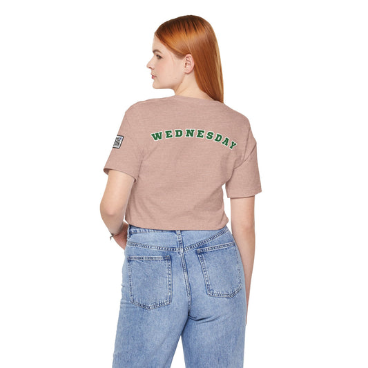Woman wearing a pink Wednesday Reminder Tee with green text on the back and blue jeans, casual style shirt for everyday wear